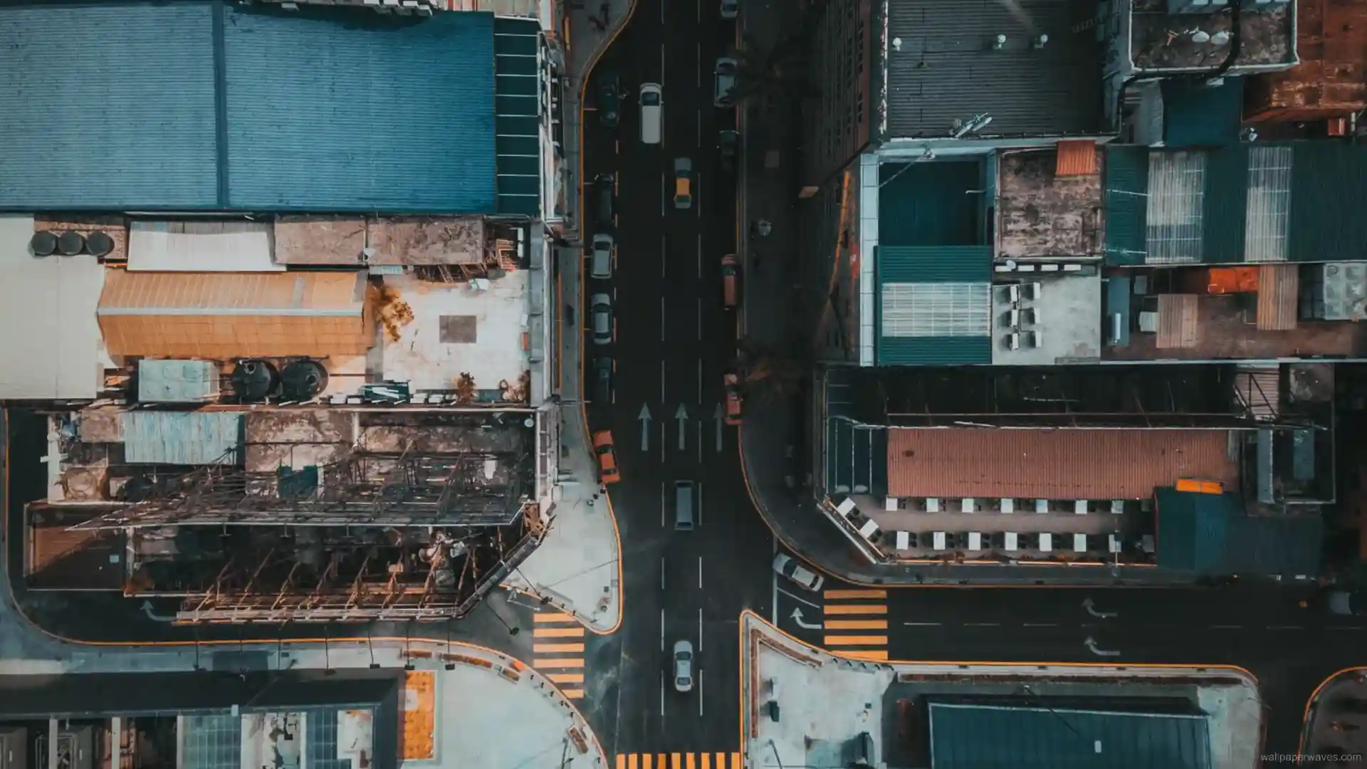 Aerial view of a glowing city street at night with neon lights and moving traffic in urban wallpaper.
