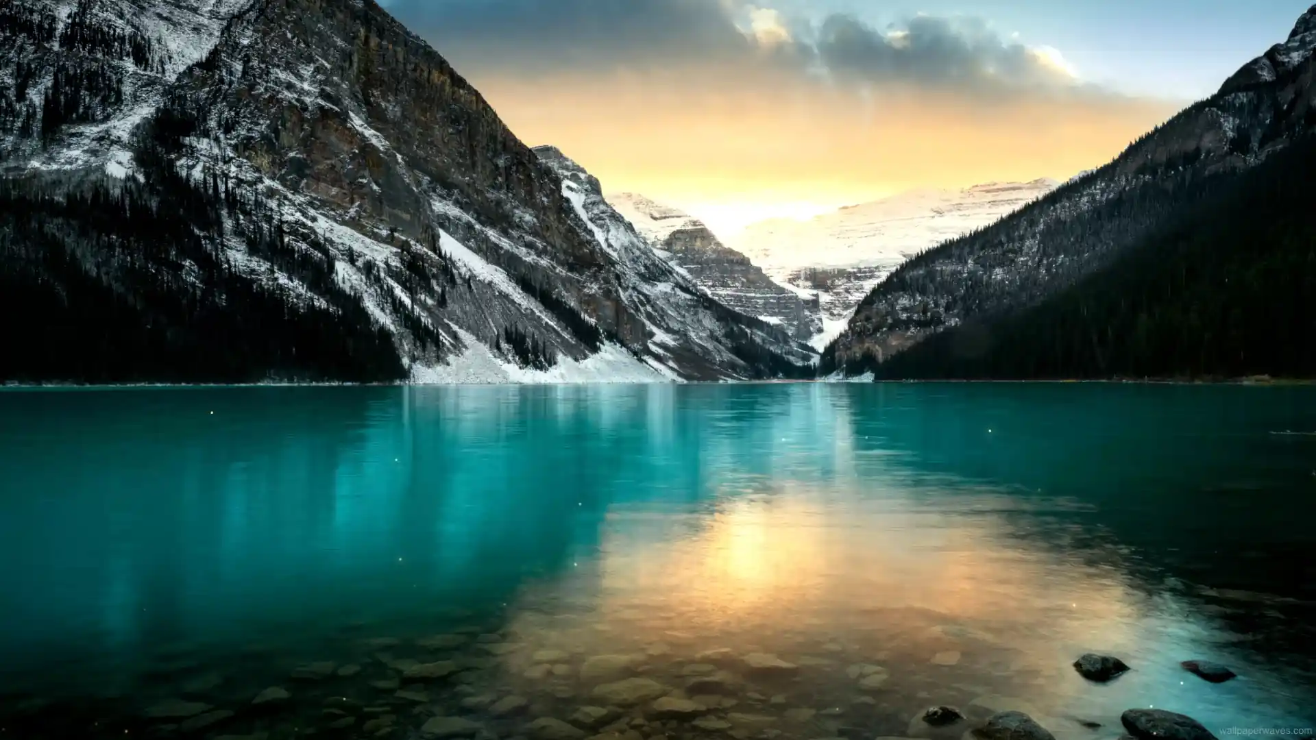 Scenic view of Lake Louise with turquoise waters reflecting snow-capped mountains and evergreen forests under a clear sky in this Canadian landscape wallpaper.