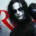 Eric Draven from The Crow, with his haunting white face paint and dark, intense gaze, standing alongside his raven in front of the bold red 'CROW' lettering