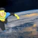 Invincible soaring through space with Earth in the background, showcasing the superhero in action with his iconic yellow and blue costume