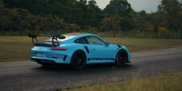 Blue Porsche 911 GT3 RS sports car with carbon spoiler and aggressive stance under city lights in a high-performance live wallpaper