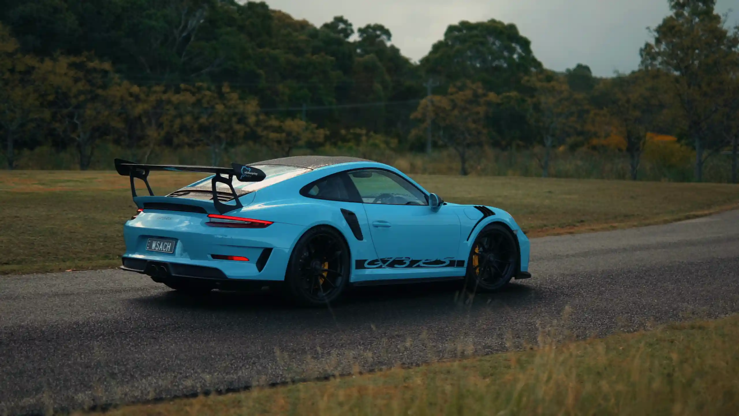 Blue Porsche 911 GT3 RS sports car with carbon spoiler and aggressive stance under city lights in a high-performance live wallpaper