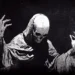 Dark Grim Reaper cloaked in shadows holding glowing scythe surrounded by swirling mist in a gothic fantasy live wallpaper