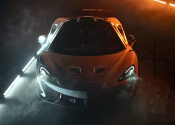 McLaren supercar glowing under dramatic cinematic lighting with golden highlights emphasizing curves and aerodynamics in a live wallpaper