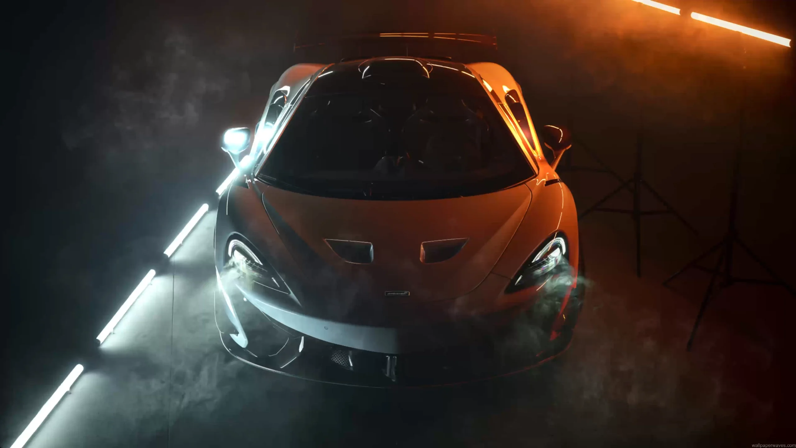 McLaren supercar glowing under dramatic cinematic lighting with golden highlights emphasizing curves and aerodynamics in a live wallpaper