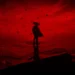 Silhouette of a samurai with sword standing on cliff under burning red sky with scattered leaves in a dramatic Ghost of Tsushima live wallpaper