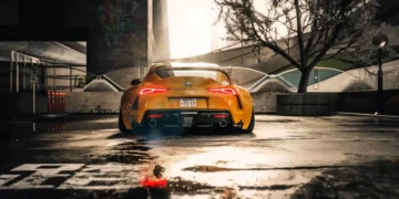 Yellow Toyota Supra parked in cinematic city setting with glowing tail lights reflecting on rain-soaked street in a live wallpaper
