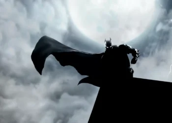 Batman standing on a rooftop in heavy rain with his cape flowing, lit by a bright full moon and lightning in a dark Gotham sky live wallpaper