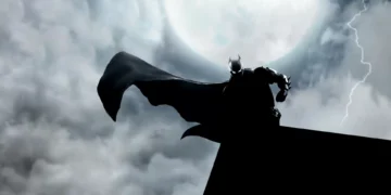 Batman standing on a rooftop in heavy rain with his cape flowing, lit by a bright full moon and lightning in a dark Gotham sky live wallpaper