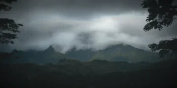 Dark storm clouds over misty green mountains with gentle rain falling and moody atmosphere live wallpaper