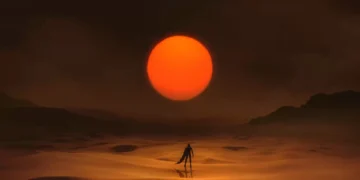 Silhouette of a lone figure walking across glowing sand dunes beneath a massive red sun in a cinematic desert scene live wallpaper.