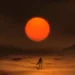 Silhouette of a lone figure walking across glowing sand dunes beneath a massive red sun in a cinematic desert scene live wallpaper.