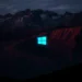 Neon blue Windows logo glitching above dark red mountains under a stormy night sky live wallpaper