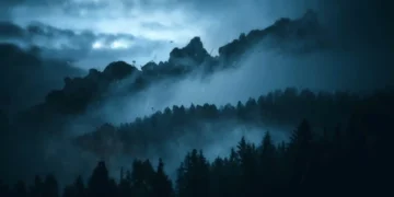 dark misty mountain forest landscape with pine trees and fog drifting across valley during rainy storm, dramatic blue atmospheric lighting with cinematic nature scenery live wallpaper