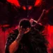 Guts from Berserk standing with massive sword in dark red demonic aura, shadow beast with glowing red eyes looming above, intense dark fantasy anime battle atmosphere live wallpaper