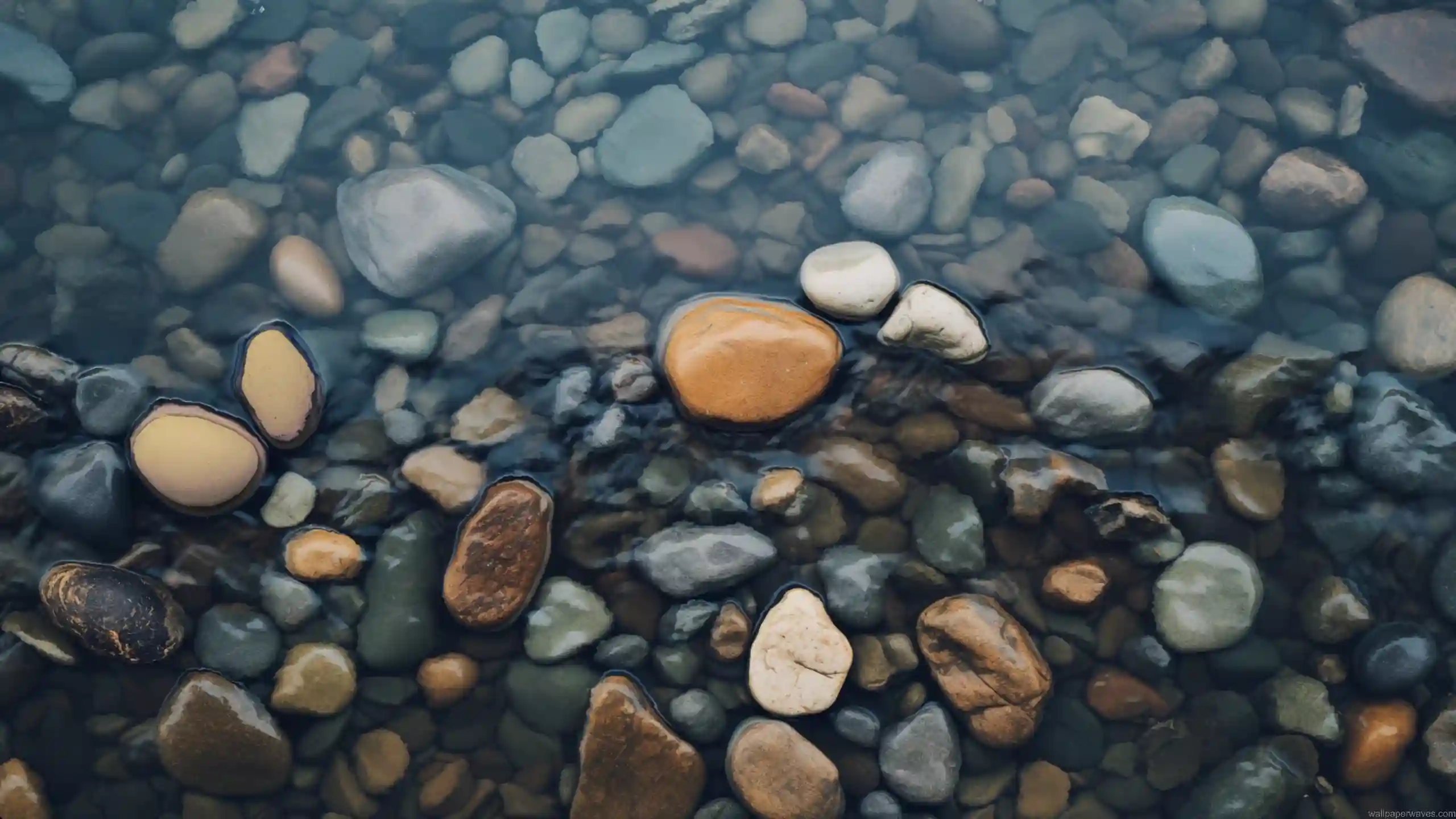 Clear river water over smooth natural pebbles with soft ripples and earthy tones creating calm relaxing nature aesthetic wallpaper