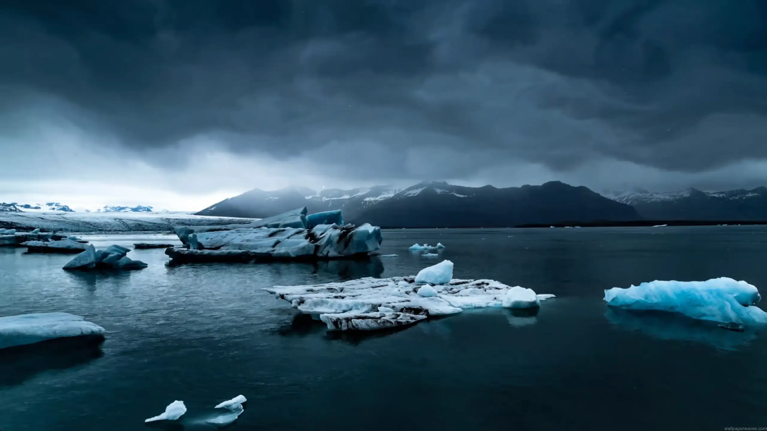 arctic glacier floating ice in calm dark water with mountains and cloudy sky peaceful cold landscape wallpaper
