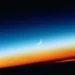 Peaceful crescent moon above a colorful sunset horizon with stars emerging across a vibrant twilight sky live wallpaper.