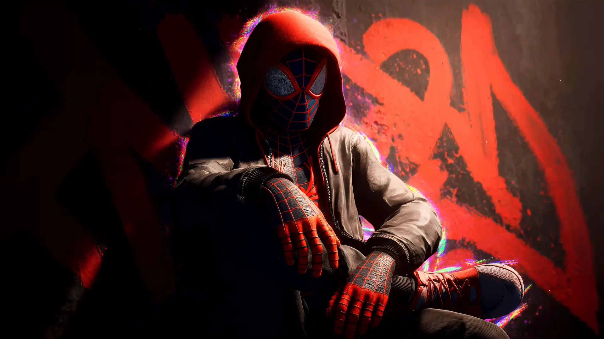 Miles Morales wearing a red hoodie over his Spider-Man suit while sitting against a graffiti wall in Spider-Man Miles Morales Live Wallpaper.