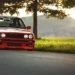 BMW E30 Red Stance Live Wallpaper 10 Lowered red BMW E30 with deep-dish wheels parked beside a tree during golden hour live wallpaper.