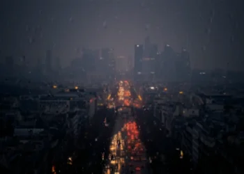 Rainy city viewed through a window covered in raindrops with blurred glowing lights live wallpaper