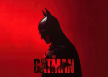 The Batman standing in profile against a dramatic red background with falling rain cinematic live wallpaper.