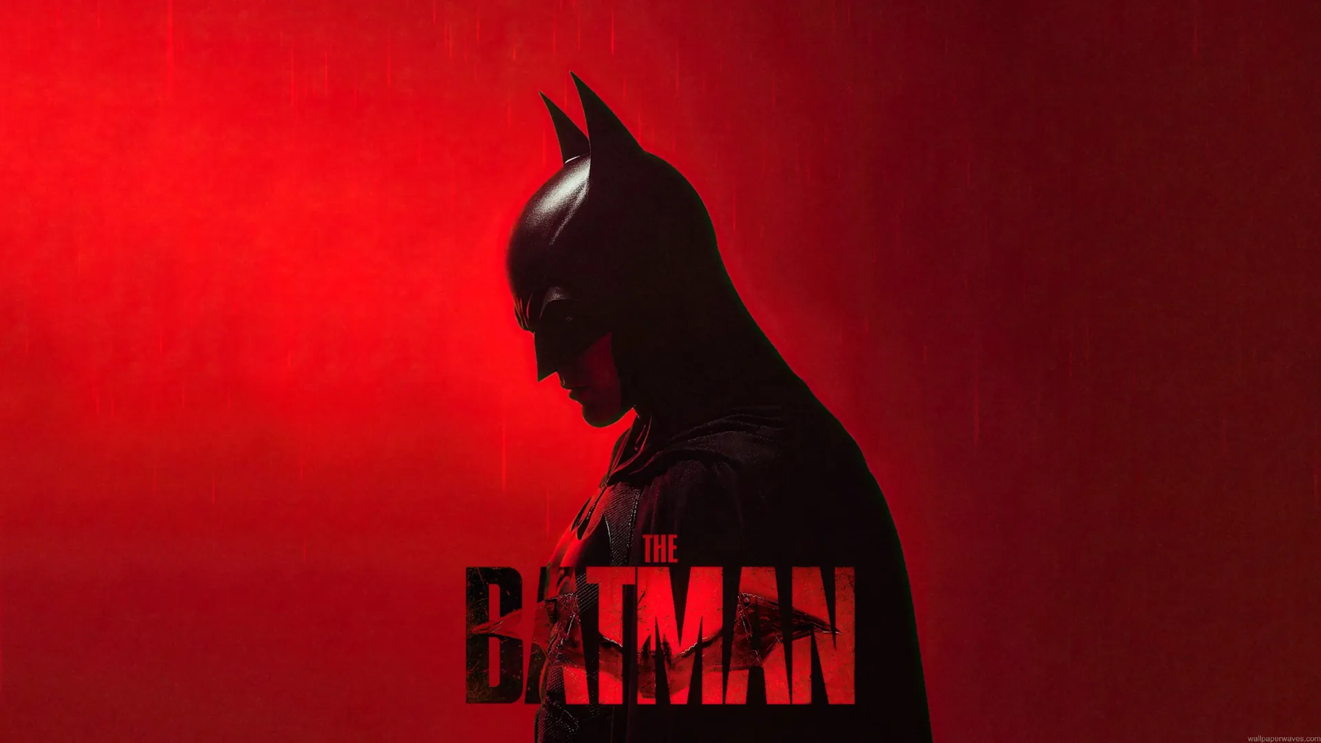 The Batman standing in profile against a dramatic red background with falling rain cinematic live wallpaper.