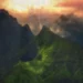 Green mountains covered in rain and mist beneath dramatic clouds and a glowing orange sunset live wallpaper