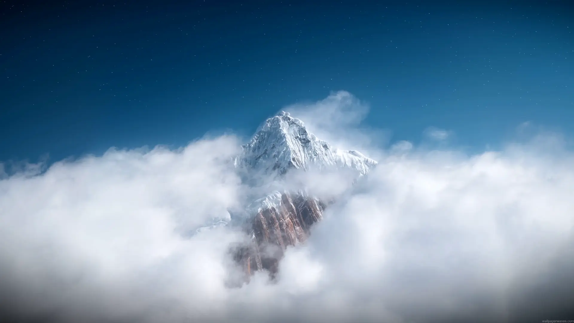 Majestic snow-covered mountain peak rising above thick white clouds beneath a deep blue starry sky in a peaceful scenic nature live wallpaper.